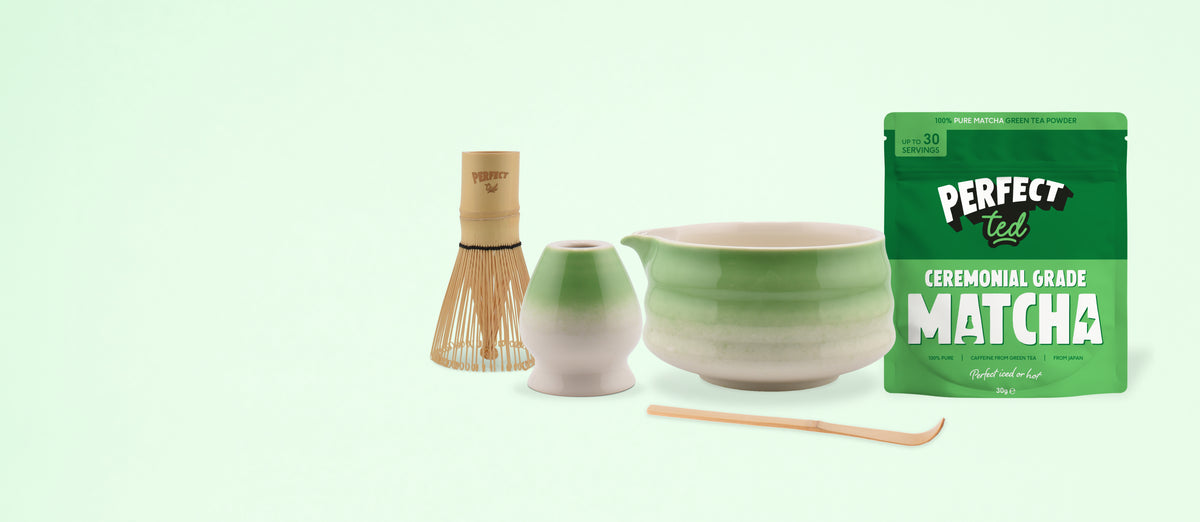 a bowl and a cup next to a bamboo whisk