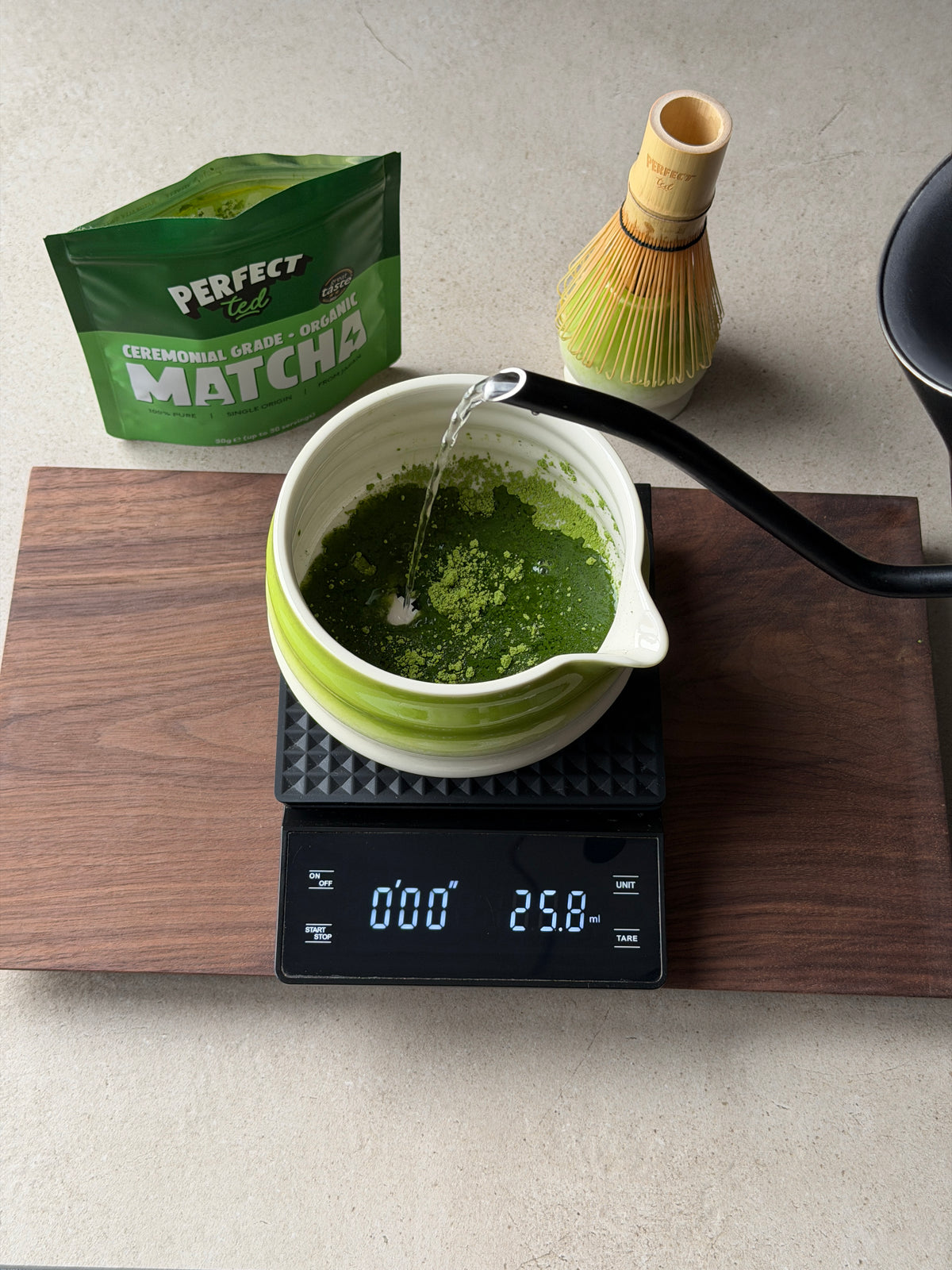 a green tea being poured into a cup on a scale