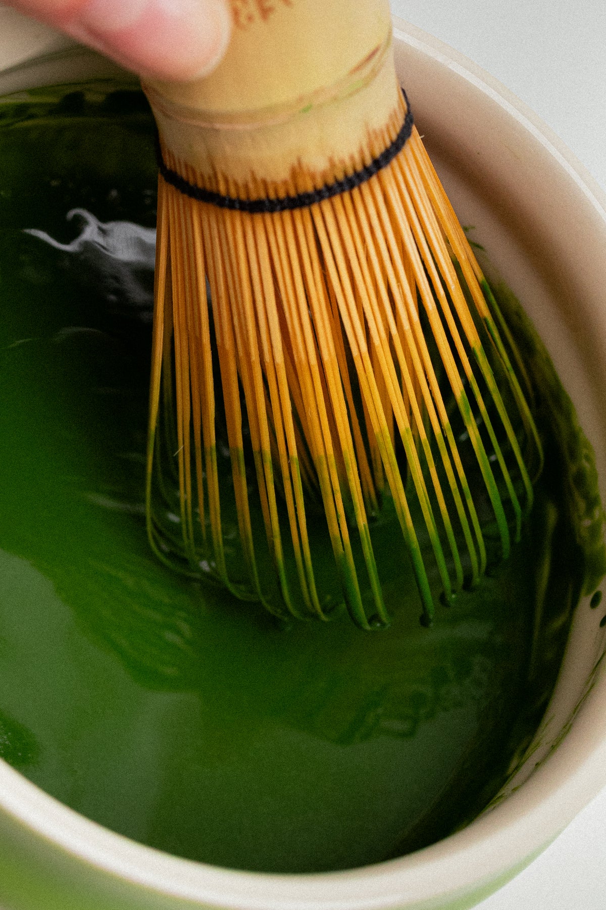 a whisk with green liquid in a bowl