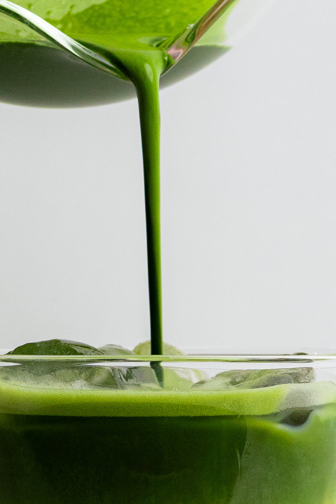 a green liquid being poured into a glass