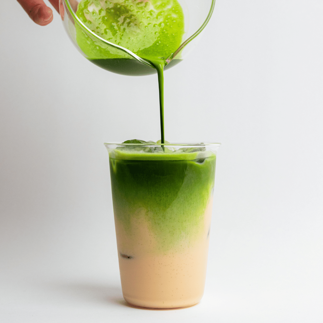 a person pouring green liquid into a glass